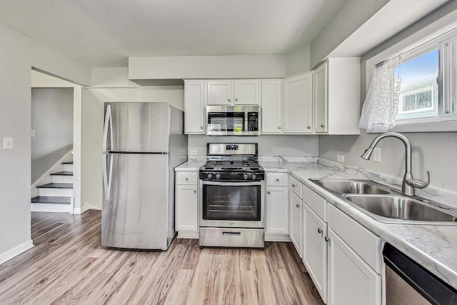 kitchen featuring white cabinets, stainless steel appliances, light hardwood / wood-style floors, and sink