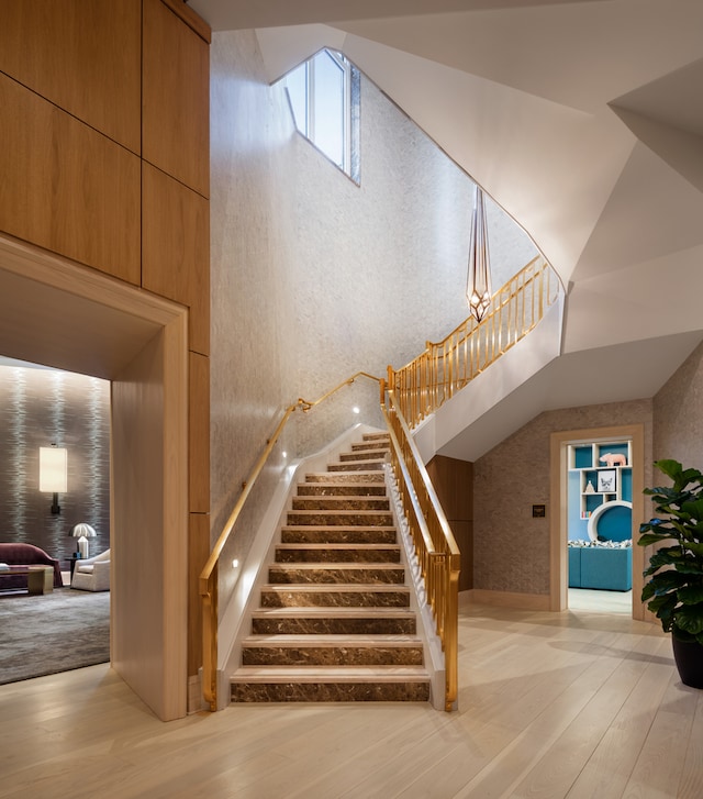 stairs featuring a high ceiling, hardwood / wood-style flooring, and a notable chandelier