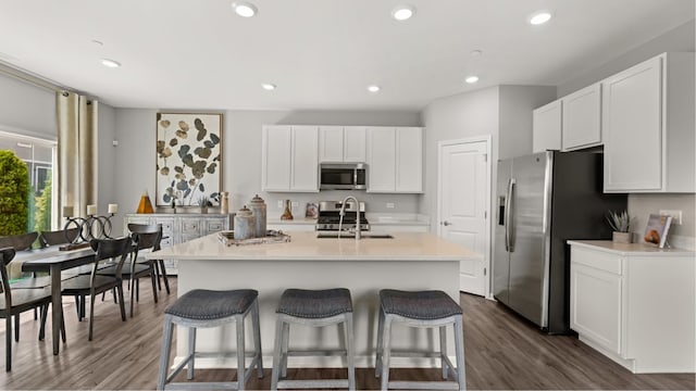 kitchen with white cabinets, a kitchen island with sink, sink, and appliances with stainless steel finishes