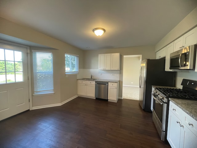 kitchen featuring backsplash, dark wood-type flooring, stainless steel appliances, sink, and white cabinets