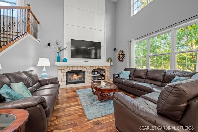 living room featuring hardwood / wood-style floors, a stone fireplace, and a towering ceiling