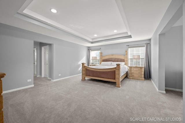 carpeted bedroom featuring multiple windows and a tray ceiling