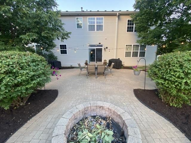 rear view of property with a fire pit and a patio