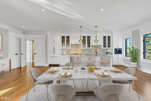 dining room with light hardwood / wood-style floors, ornamental molding, and sink