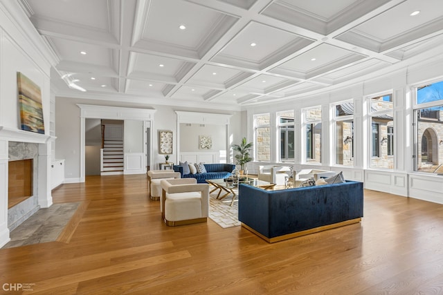 living room with beam ceiling, a high end fireplace, coffered ceiling, and hardwood / wood-style floors