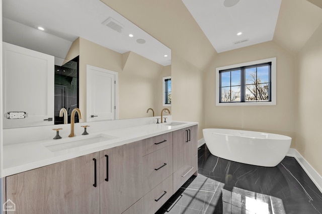 bathroom featuring a bathing tub, lofted ceiling, and vanity