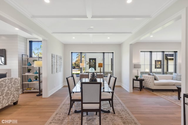 dining area with beamed ceiling, light wood-type flooring, and crown molding