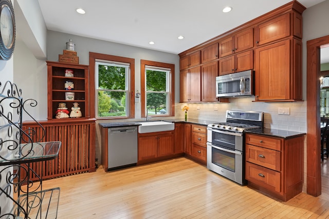 kitchen featuring stainless steel appliances, sink, tasteful backsplash, and light hardwood / wood-style flooring