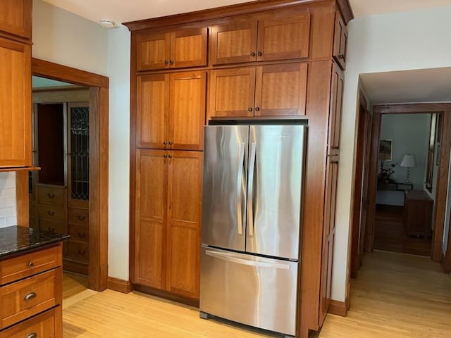 kitchen featuring dark stone counters, stainless steel fridge, and light hardwood / wood-style flooring