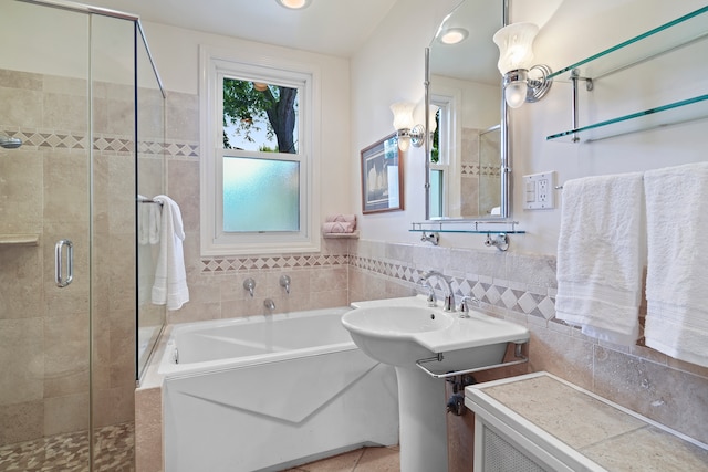 bathroom featuring shower with separate bathtub and tile walls