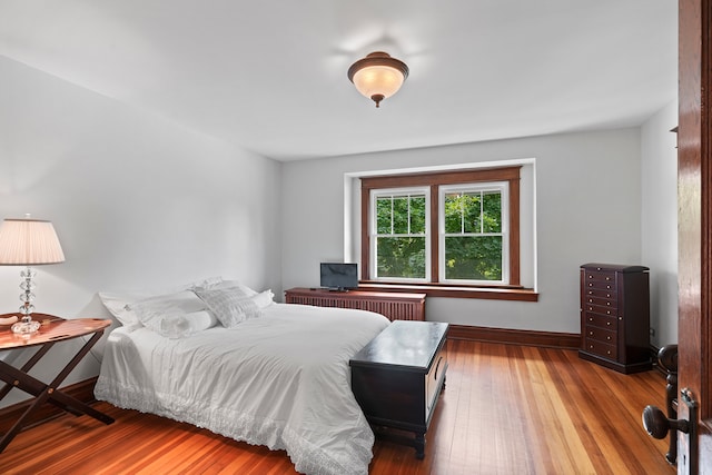 bedroom with radiator heating unit and hardwood / wood-style flooring