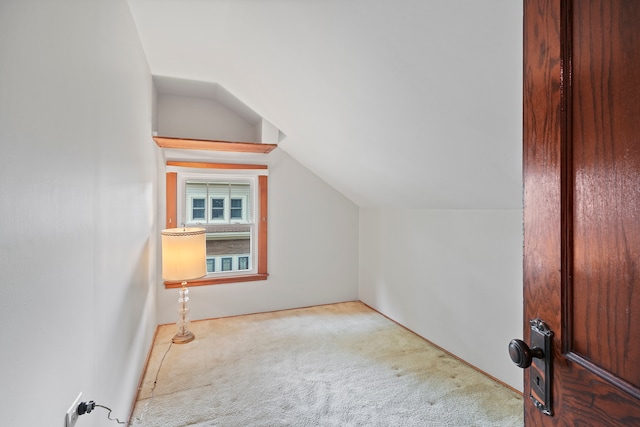 additional living space featuring vaulted ceiling and light carpet