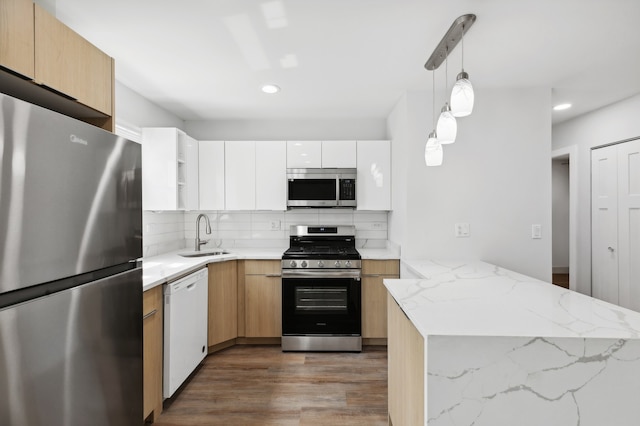 kitchen with decorative light fixtures, light stone counters, sink, appliances with stainless steel finishes, and white cabinets