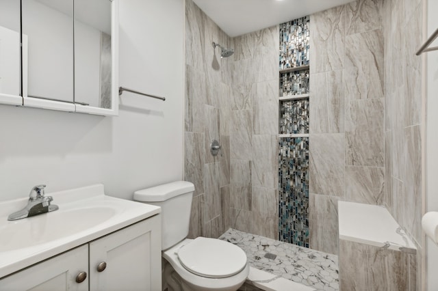 bathroom featuring toilet, a tile shower, and vanity