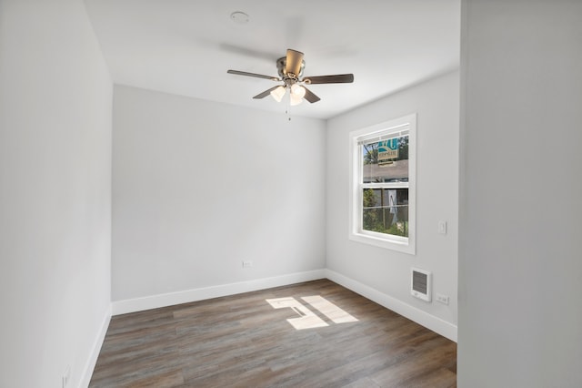 unfurnished room featuring dark wood-type flooring, ceiling fan, and heating unit