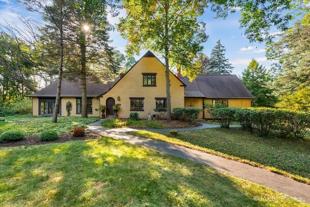 tudor house featuring a chimney and a front yard