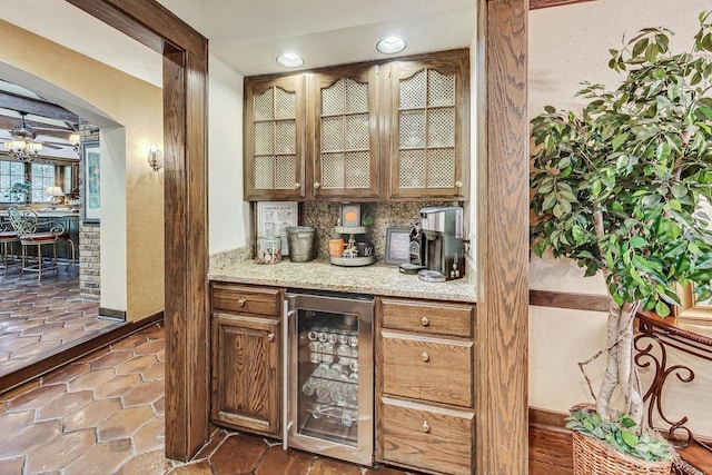 bar featuring light stone countertops, ceiling fan, tasteful backsplash, and beverage cooler