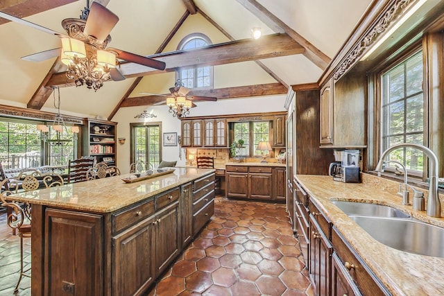 kitchen featuring sink, beamed ceiling, a wealth of natural light, and a kitchen island