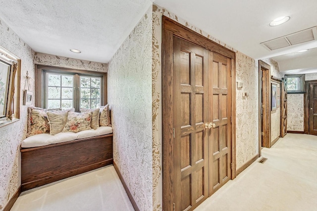 hallway featuring light carpet and a textured ceiling