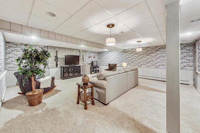 living room with brick wall, a drop ceiling, and light carpet