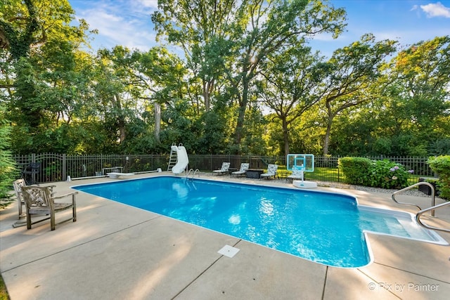 view of swimming pool featuring a patio, a water slide, and a diving board