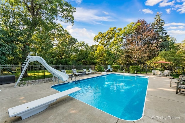 view of swimming pool featuring a water slide, a diving board, and a patio area