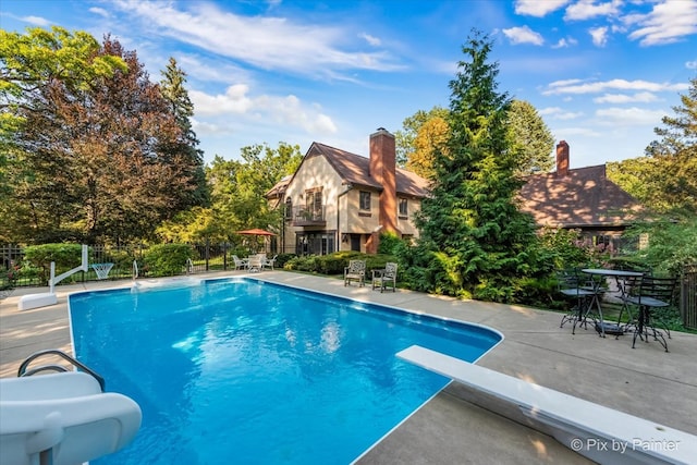 view of pool with a patio and a diving board