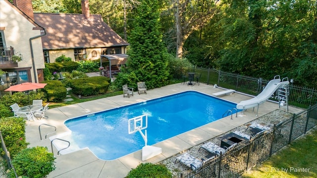 view of swimming pool featuring a patio, a water slide, and a diving board