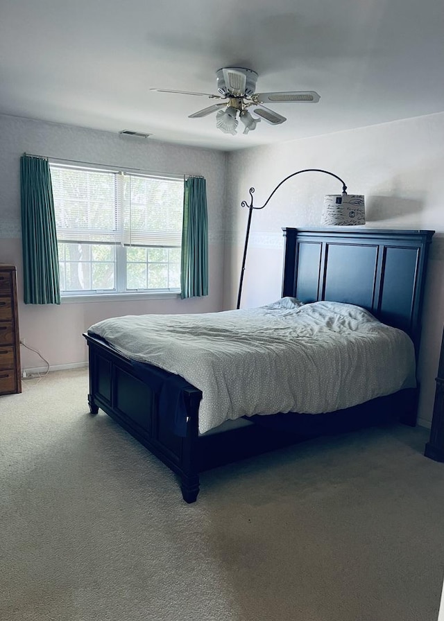 bedroom with visible vents, light colored carpet, and ceiling fan