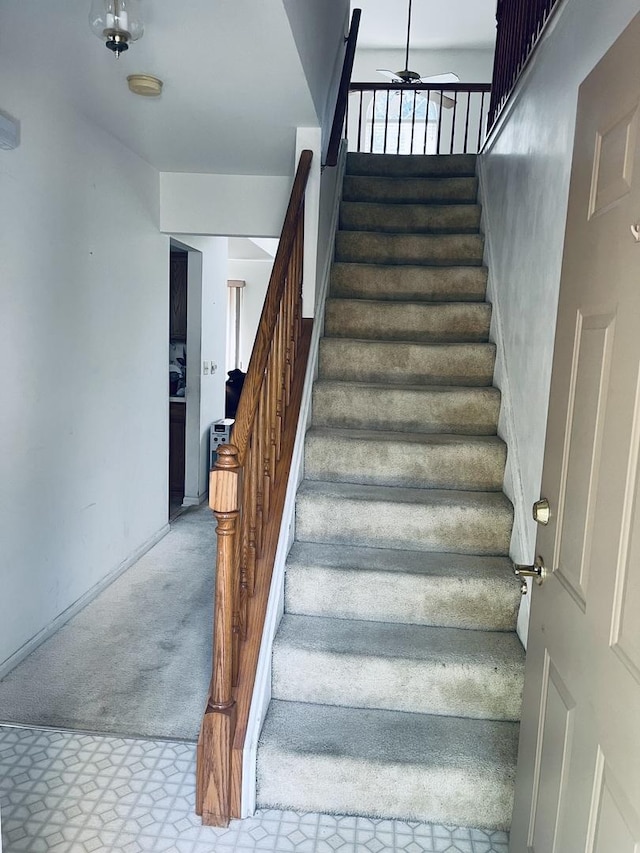 stairway with carpet floors and a ceiling fan