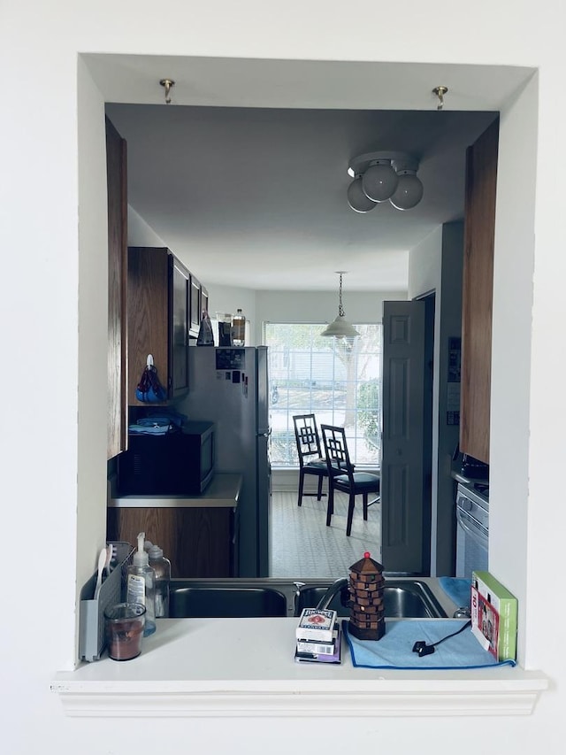 kitchen featuring black appliances, wood finished floors, hanging light fixtures, and light countertops