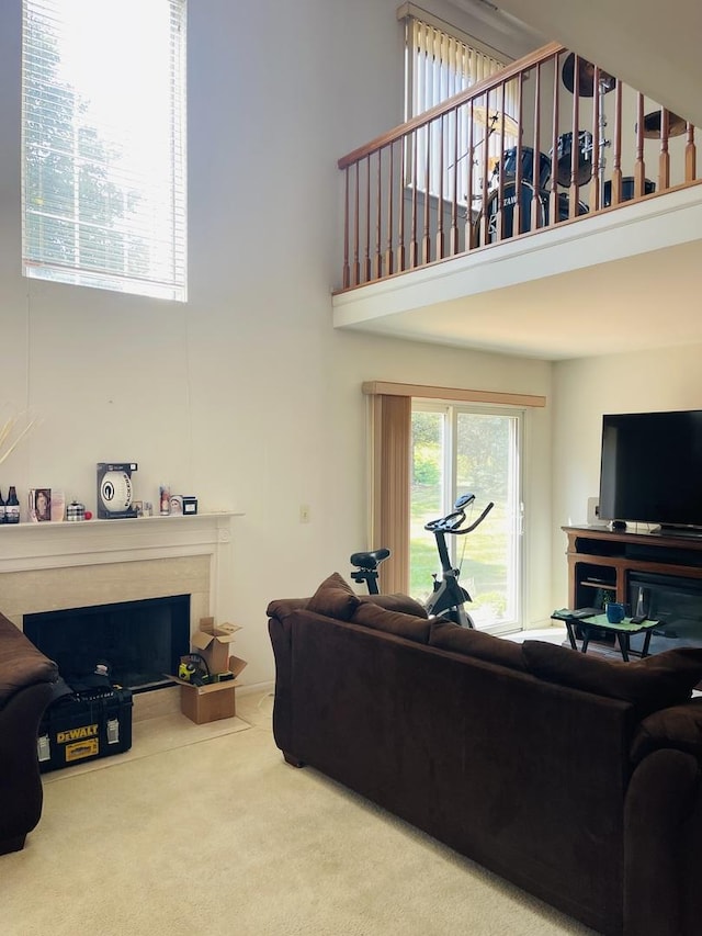 carpeted living area with a fireplace and a towering ceiling