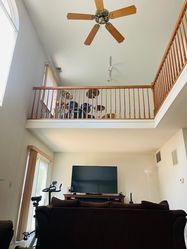 living room featuring ceiling fan and a towering ceiling