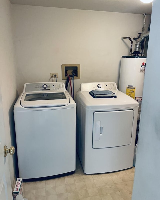 clothes washing area featuring water heater, washing machine and clothes dryer, and laundry area
