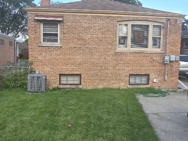 view of side of property featuring a yard and central AC