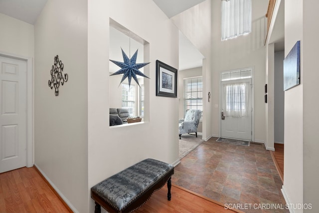 entrance foyer featuring a towering ceiling, baseboards, and wood finished floors