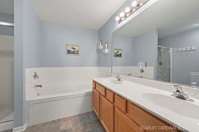 full bathroom featuring double vanity, a stall shower, a sink, and a bath