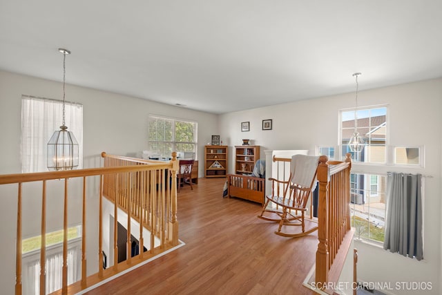 hall featuring an inviting chandelier, wood finished floors, and an upstairs landing