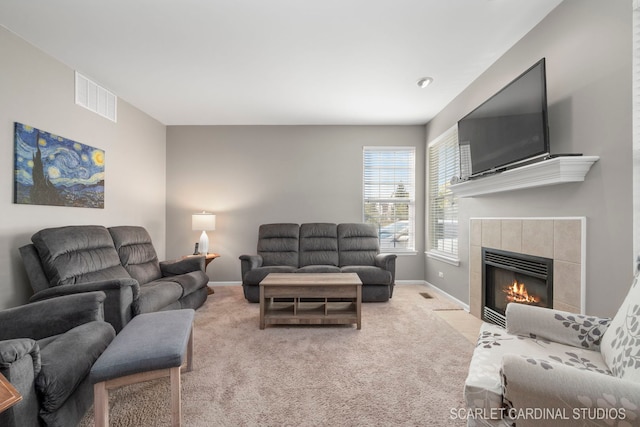 carpeted living area featuring baseboards, visible vents, and a tile fireplace