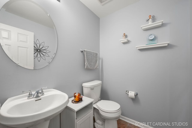 half bath featuring baseboards, a sink, and toilet