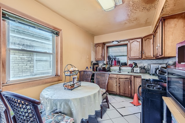 kitchen featuring a healthy amount of sunlight, sink, light tile patterned flooring, and decorative backsplash