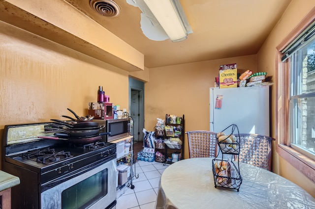 kitchen featuring light tile patterned floors, white fridge, and range with gas cooktop