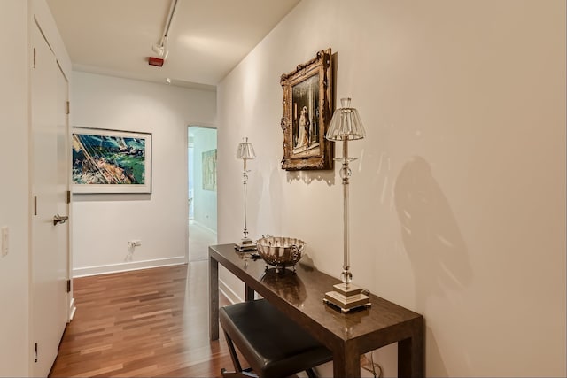 corridor with hardwood / wood-style flooring and rail lighting