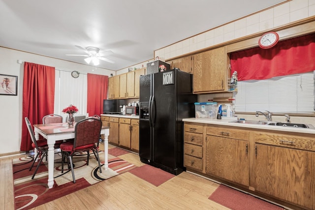 kitchen featuring light hardwood / wood-style floors, ceiling fan, black fridge, and sink