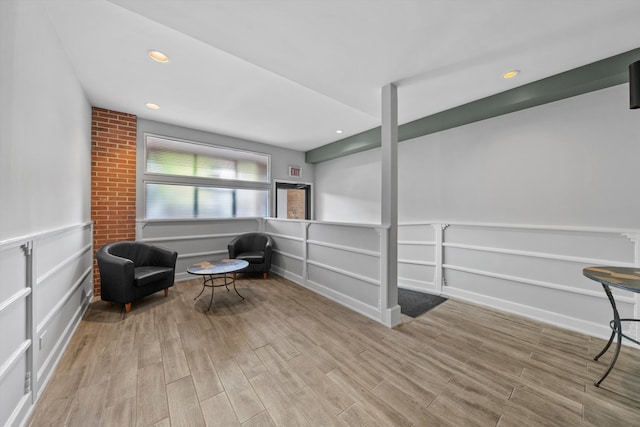 living area featuring brick wall and light hardwood / wood-style flooring