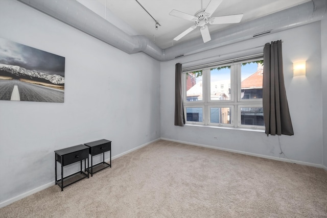 carpeted spare room with track lighting and ceiling fan