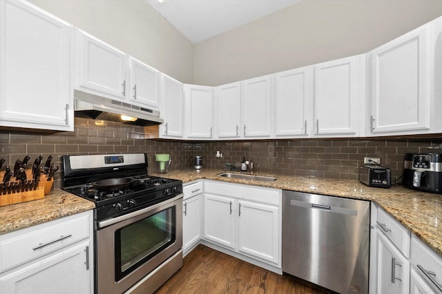 kitchen featuring dark wood-type flooring, white cabinets, stainless steel appliances, and decorative backsplash