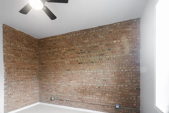 empty room featuring brick wall and ceiling fan