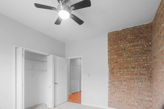 unfurnished bedroom featuring light hardwood / wood-style flooring, ceiling fan, and brick wall