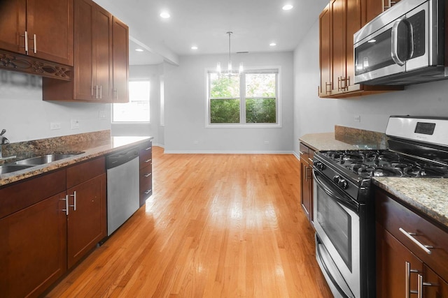 kitchen with light wood-type flooring, stainless steel appliances, and stone countertops